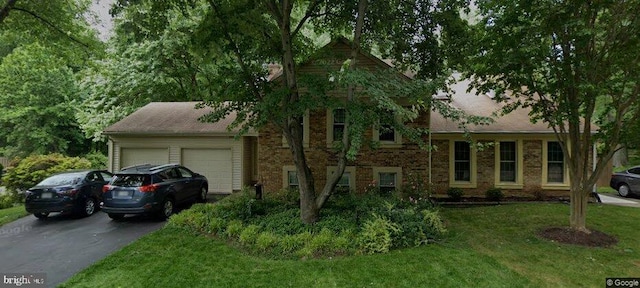 tri-level home featuring a garage, driveway, a front lawn, and brick siding