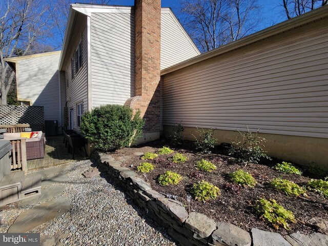 view of side of property featuring a chimney and central AC
