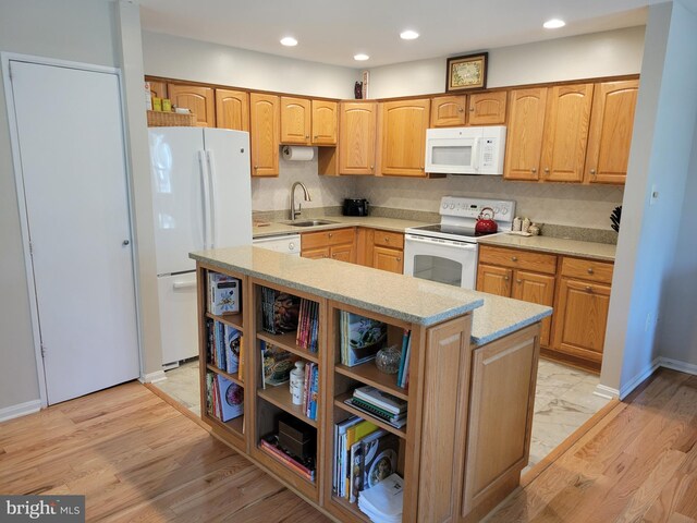 kitchen with open shelves, a kitchen island, white appliances, a sink, and light wood-style flooring
