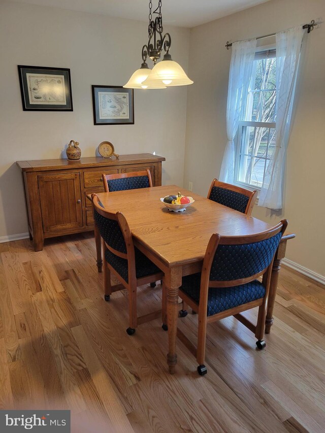 dining area with baseboards and light wood-style flooring