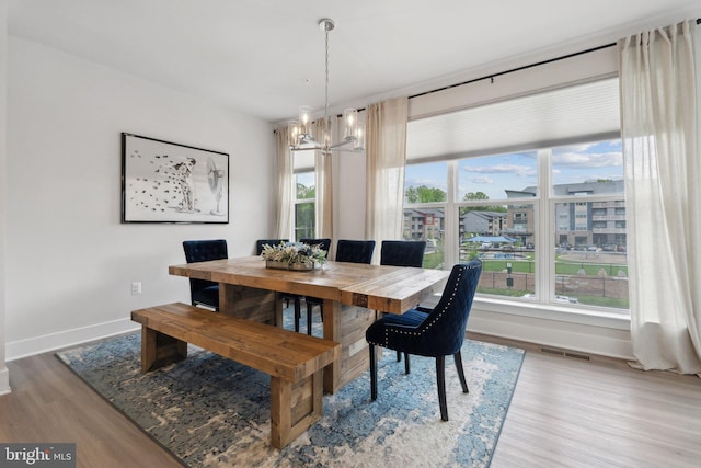 dining room featuring visible vents, baseboards, wood finished floors, and a chandelier