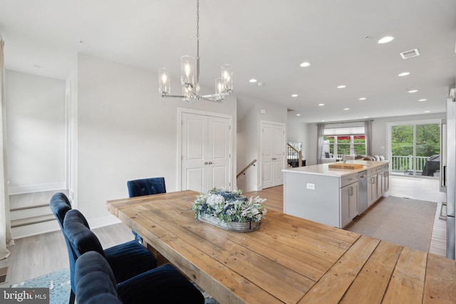 dining area featuring visible vents, light wood-style floors, baseboards, recessed lighting, and a notable chandelier