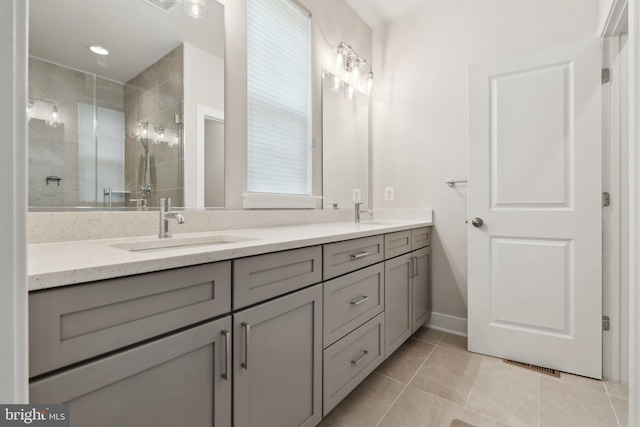 bathroom featuring double vanity, visible vents, tile patterned flooring, a stall shower, and a sink