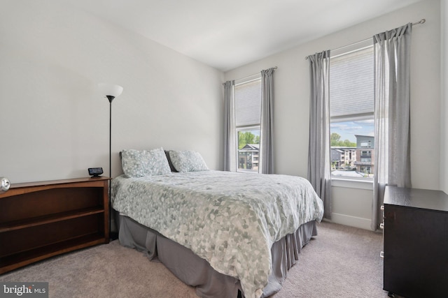 bedroom with light colored carpet and baseboards