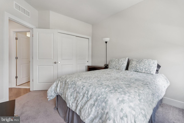 carpeted bedroom with baseboards, visible vents, and a closet
