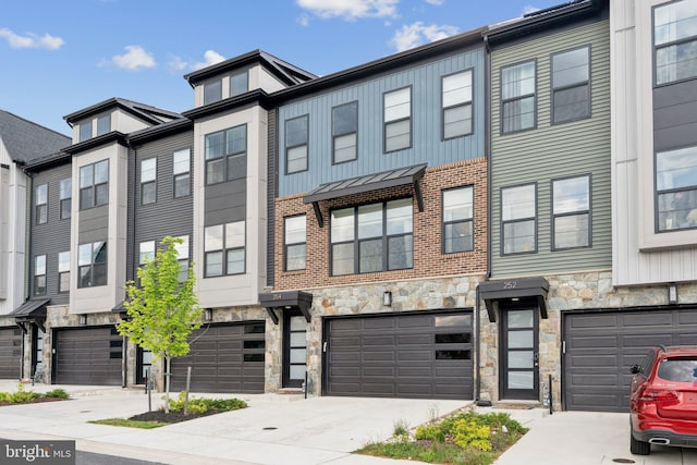 townhome / multi-family property with a garage, driveway, and stone siding