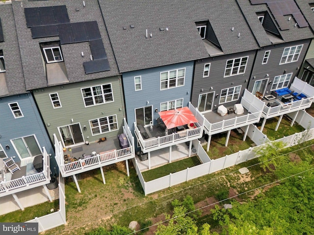 back of property featuring roof with shingles, solar panels, and a deck
