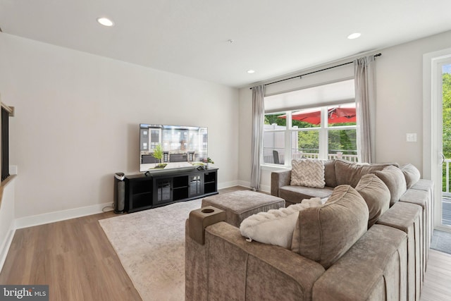 living area with baseboards, recessed lighting, and light wood-style flooring