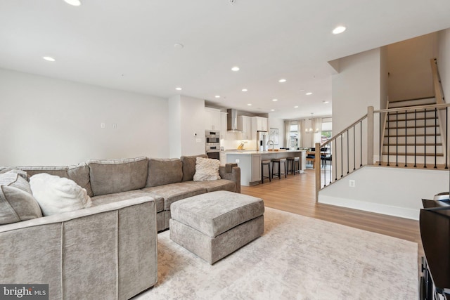 living room featuring recessed lighting, light wood-style flooring, and stairway