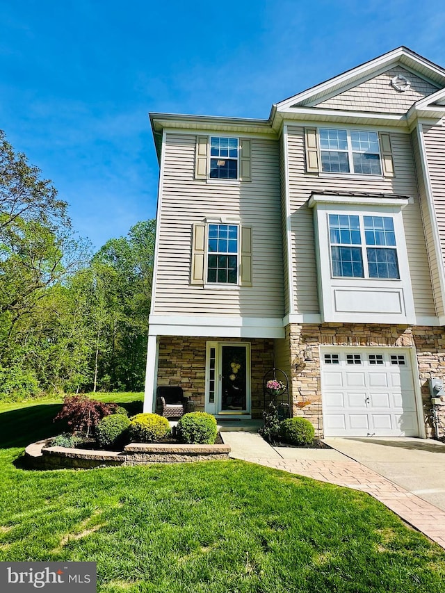 townhome / multi-family property with driveway, a front yard, and stone siding