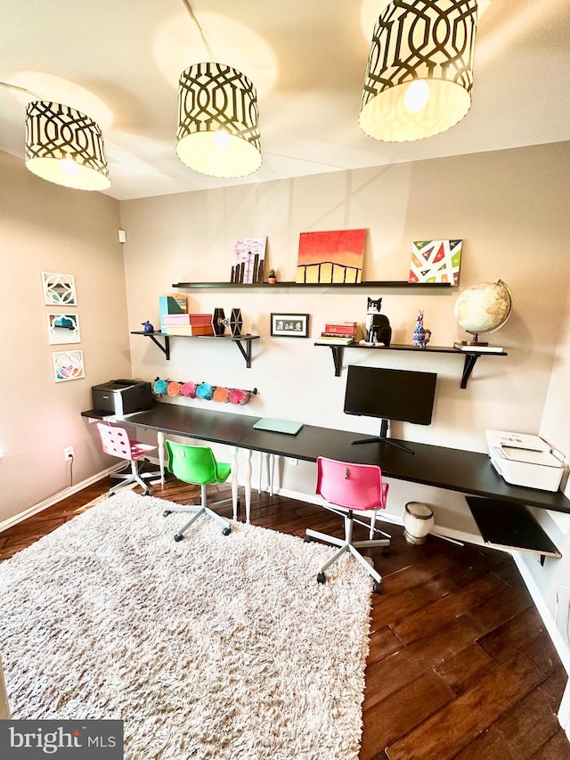 office space with baseboards, built in desk, and wood finished floors