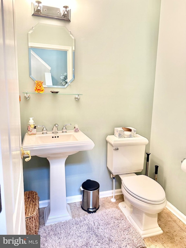 bathroom with baseboards, a sink, and toilet