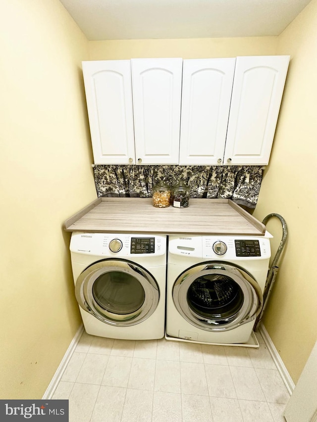 clothes washing area featuring baseboards, cabinet space, light tile patterned floors, and washing machine and dryer
