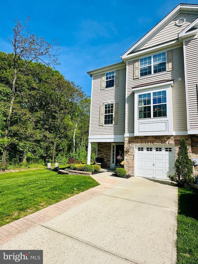 multi unit property with an attached garage, a front yard, driveway, and stone siding