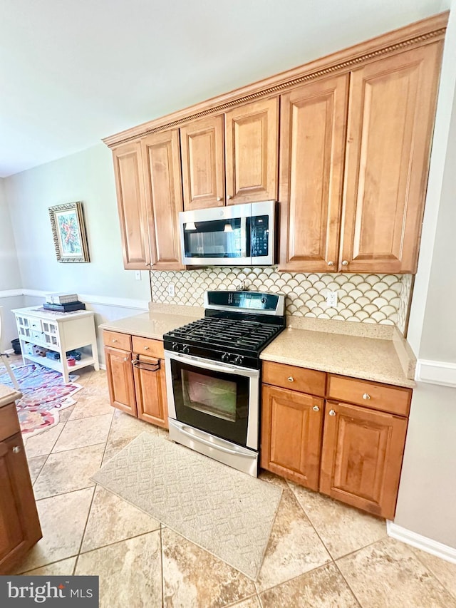 kitchen with light countertops, baseboards, backsplash, and stainless steel appliances
