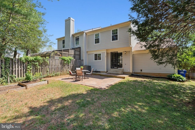 rear view of property featuring a patio area, fence, a yard, and a chimney