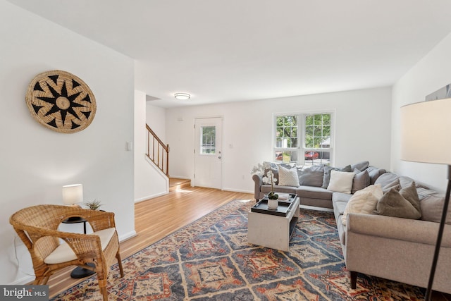 living room featuring baseboards, wood finished floors, and stairway