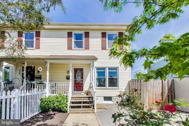 townhome / multi-family property featuring a porch and fence