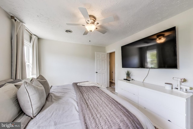 bedroom with visible vents, a ceiling fan, and a textured ceiling