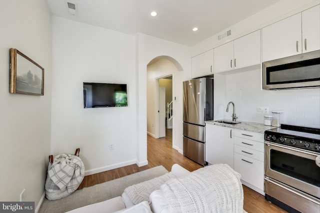 kitchen with visible vents, appliances with stainless steel finishes, arched walkways, a sink, and white cabinets