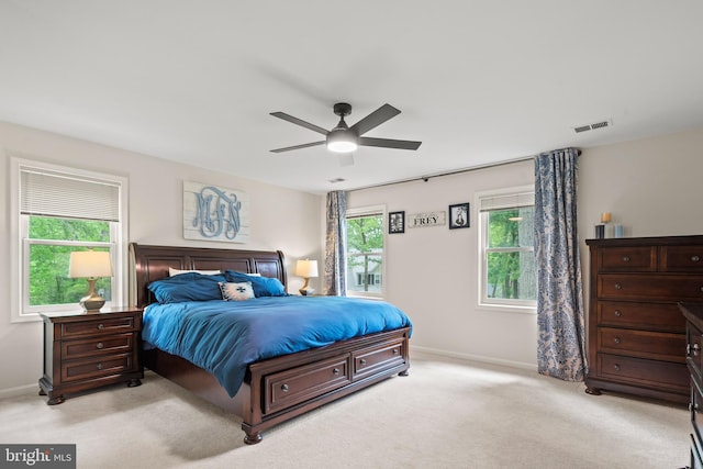 bedroom with a ceiling fan, baseboards, visible vents, and light carpet