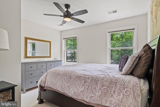 bedroom with a ceiling fan, light colored carpet, and visible vents