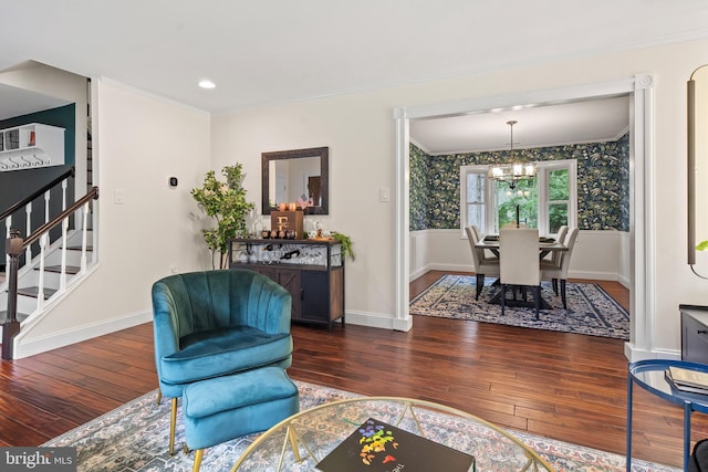 living area with crown molding, stairs, hardwood / wood-style floors, and an inviting chandelier