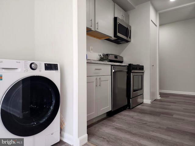 3811 Saint Barnabas Rd Unit T2, Suitland, MD 20746 - laundry area with washer / dryer, wood finished floors, and baseboards