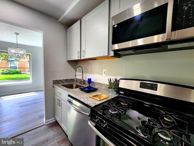 3811 Saint Barnabas Rd Unit T2, Suitland, MD 20746 - kitchen with stainless steel appliances, a sink, light wood finished floors, light stone counters, and white cabinetry