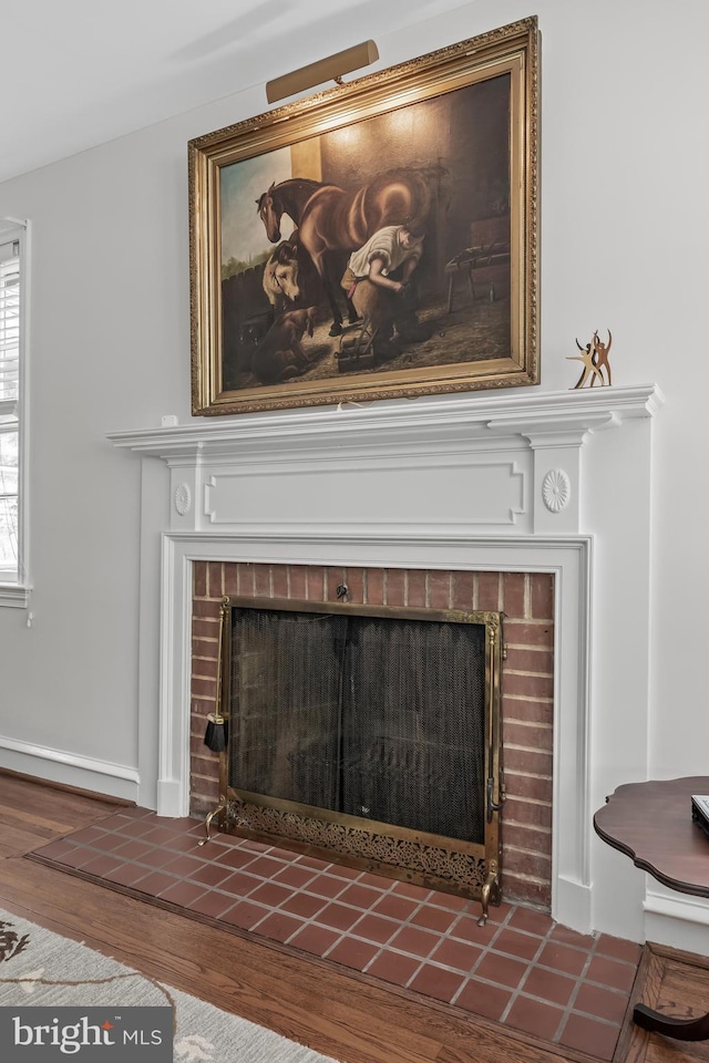 interior details with a tiled fireplace, baseboards, and wood finished floors