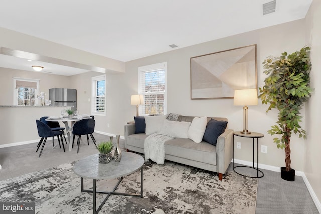 living room with carpet floors, baseboards, and visible vents