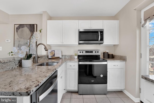 kitchen featuring stainless steel appliances, light stone countertops, white cabinetry, and a sink