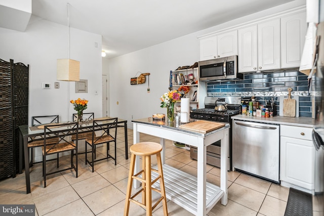 5217 Greene St, Philadelphia, PA 19144 - kitchen featuring backsplash, stainless steel appliances, white cabinetry, and light tile patterned floors