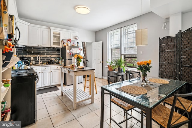 5217 Greene St, Philadelphia, PA 19144 - kitchen with stainless steel appliances, white cabinetry, light tile patterned floors, tasteful backsplash, and glass insert cabinets
