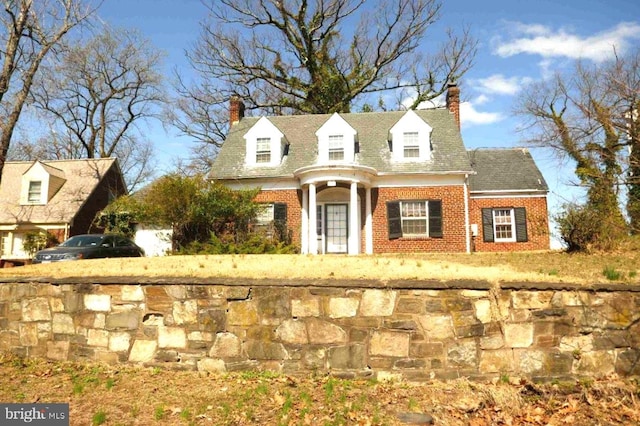 view of front of house featuring a chimney and brick siding