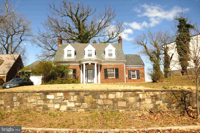 new england style home with brick siding and a chimney