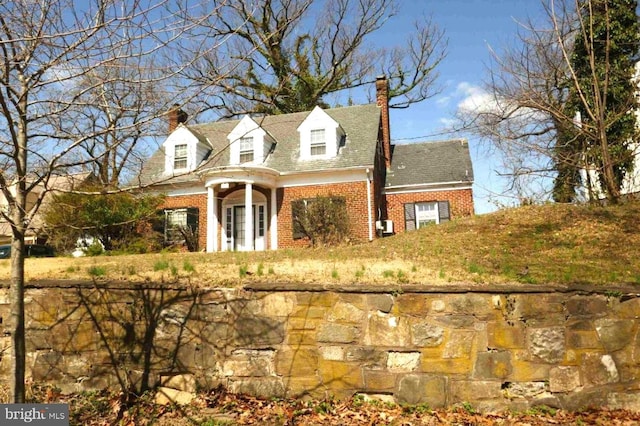 cape cod house featuring brick siding and a chimney