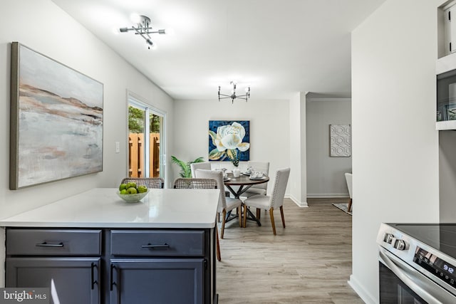 kitchen featuring light wood-type flooring, light countertops, baseboards, electric stove, and a notable chandelier