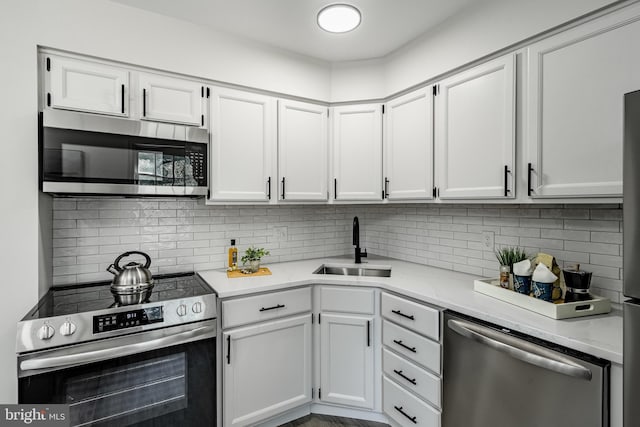 kitchen featuring light stone counters, a sink, stainless steel appliances, white cabinetry, and backsplash