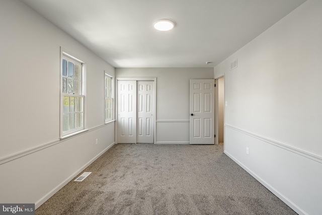 unfurnished bedroom with carpet flooring, baseboards, visible vents, and a closet