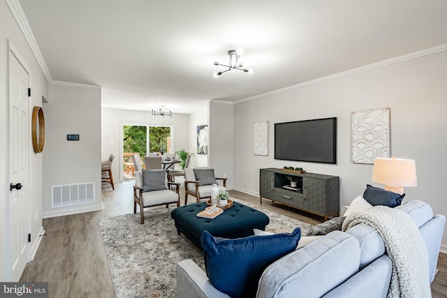 living area featuring visible vents, baseboards, wood finished floors, and an inviting chandelier
