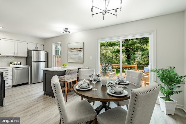 dining room with an inviting chandelier, light wood-type flooring, and a wealth of natural light
