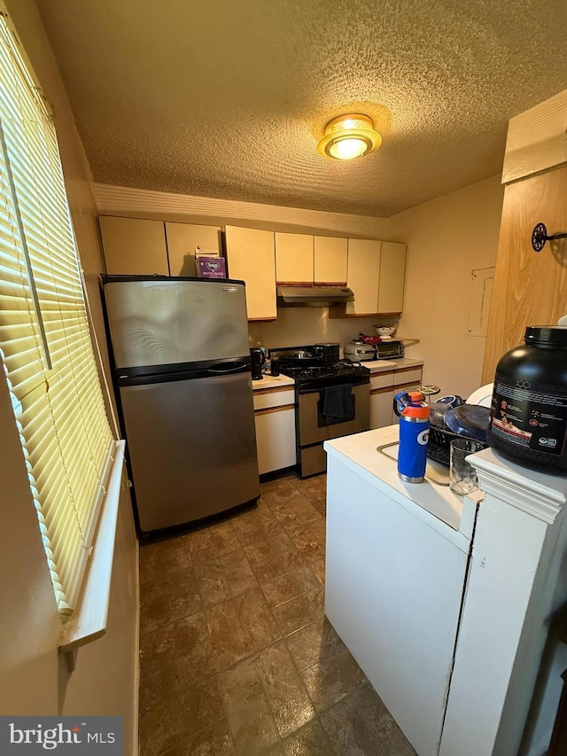 kitchen with appliances with stainless steel finishes, light countertops, a textured ceiling, white cabinetry, and under cabinet range hood