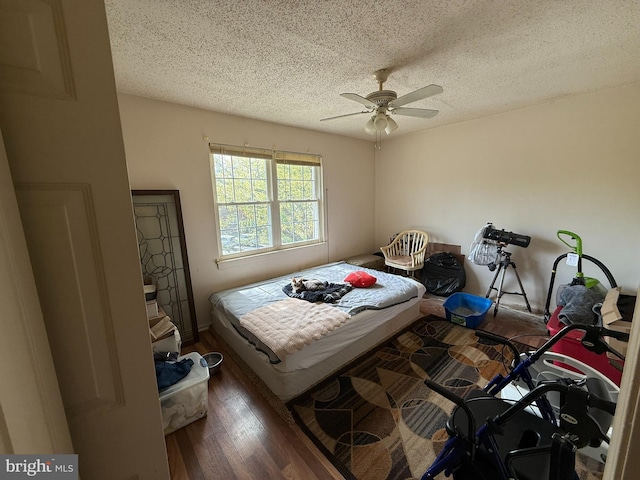 bedroom with a textured ceiling, ceiling fan, and wood finished floors