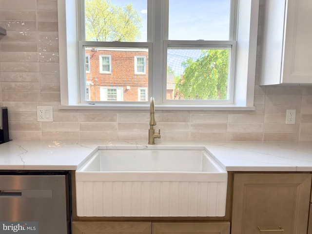 room details featuring a sink, light stone counters, decorative backsplash, and dishwasher