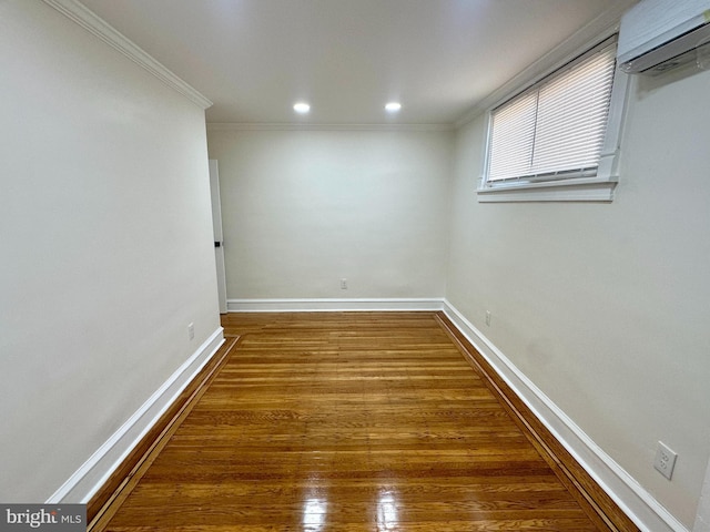 empty room featuring crown molding, wood finished floors, baseboards, an AC wall unit, and recessed lighting