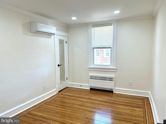 unfurnished room featuring crown molding, heating unit, wood finished floors, baseboards, and a wall mounted air conditioner