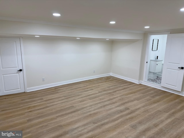 finished below grade area featuring crown molding, recessed lighting, baseboards, and wood finished floors