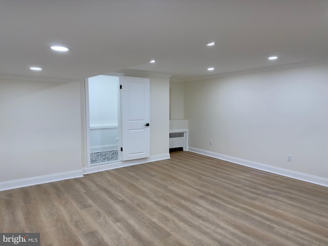 basement featuring baseboards, ornamental molding, wood finished floors, and radiator