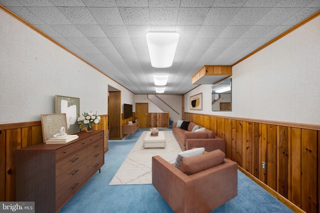 living room with carpet floors, crown molding, wood walls, and wainscoting